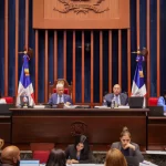 El ministro de Justicia tendrá como principales atribuciones coordinar las políticas públicas contra la criminalidad, gestionar la colaboración del Poder Ejecutivo con el sistema judicial, representar y defender al Estado en sedes jurisdiccionales y foros arbitrales, así como coordinar el Sistema Nacional de Derechos Humanos y dar respuesta a los requerimientos de organismos internacionales en esta materia. La aprobación de esta ley representa un paso trascendental en el proceso de modernización institucional del país, y responde a la necesidad de contar con un ente especializado que coordine los esfuerzos del Estado en materia judicial, penitenciaria y de derechos humanos. En los trabajos legislativos de este miércoles, el Pleno del Senado aprobó las modificaciones al proyecto de ley que modifica la Ley núm. 225-20, Ley General de Gestión Integral y Coprocesamiento de Residuos Sólidos, iniciativa presentada por los senadores Ramón Rogelio Genao Durán y Ginnette Bournigal de Jiménez. La iniciativa legislativa busca modificar la Ley núm. 225-20 para fortalecer el marco normativo que regula la gestión integral y sostenible de los residuos sólidos en el país. Con esta ley se promueve la reducción, reutilización, reciclaje y aprovechamiento de residuos, así como una mejor regulación de su recolección y disposición, con el fin de proteger la salud, el medio ambiente y reducir los gases de efecto invernadero. La modificación de esta ley considera necesario alinear su contenido con los objetivos de reducción del impacto ambiental de los residuos, mediante la implementación de regulaciones más estrictas sobre el uso de materiales no biodegradables y la promoción del empleo de materiales reciclados y biodegradables. También se aprobó la ley que modifica los artículos 36, 64 y 81 de la Ley núm. 176-07, que regula el Distrito Nacional y los Municipios, con el objetivo de establecer disposiciones más claras sobre la sucesión en los cargos de alcaldes, vicealcaldes, regidores, directores, suplentes de directores y vocales de las juntas de distritos municipales. Esta iniciativa legislativa fue presentada por la senadora María Mercedes Ortiz Diloné. Entre las modificaciones introducidas por la ley, se destaca el artículo 64, relativo a la sustitución del alcalde o alcaldesa. Este establece que la vacante definitiva en el cargo de alcalde o alcaldesa será ocupada por el vicealcalde o vicealcaldesa, quien deberá prestar juramento ante el Concejo de Regidores. El presidente del Concejo de Regidores convocará una sesión extraordinaria al efecto dentro de los quince días hábiles siguientes a la ocurrencia de la vacante. Durante la sesión de este miércoles, además, el Pleno aprobó el proyecto de ley que busca elevar a la categoría de municipio al distrito municipal turístico Verón–Punta Cana, perteneciente actualmente al municipio de Higüey, provincia La Altagracia, presentada por el senador Rafael Barón Duluc Rijo. La iniciativa establece que Verón–Punta Cana ha registrado importantes transformaciones urbanas y socioeconómicas en los últimos años, lo que justifica una nueva organización política y administrativa. Entre los indicadores de su desarrollo se destacan la presencia de más de setenta hoteles, un aeropuerto internacional, un helipuerto y un robusto tejido empresarial que impulsa una de las principales actividades turísticas del país. RESOLUCIONES Los senadores aprobaron varias resoluciones, entre ellas la que solicita al presidente Luis Abinader, instruir al órgano correspondiente con el fin de construir un play de béisbol en el distrito municipal Santiago oeste, del municipio Santiago de los caballeros, provincia Santiago, iniciativa del senador Daniel Enrique de Jesús Rivera. También fue aprobada la resolución que solicita al presidente Luis Abinader instruir al órgano correspondiente con el fin de construir un polideportivo techado en el distrito municipal El Limón, municipio villa González, provincia Santiago, presentada por el senador Daniel Enrique de Jesús Rivera. Los senadores también aprobaron la resolución que reconoce a la cooperativa La Altagracia, en ocasión de su 72 aniversario, iniciativa presentada por los senadores Julito Fulcar Encarnación y Daniel Enrique de Jesús Rivera. Además, los senadores conocieron la resolución que reconoce al destacado músico, productor, compositor, cantante y arreglista, el maestro Henry Hierro, por su trascendental y fecunda labor artística y social en beneficio de la nación dominicana, iniciativa del senador Franklin Martín Romero Morillo. El Pleno también aprobó la ratificación del nombramiento diplomático de Iris Joseline Pujol Rodríguez, como embajadora extraordinaria y plenipotenciaria, concurrente, de la República Dominicana en Ucrania, con sede en la República Federal de Alemania, iniciativa del Poder Ejecutivo.