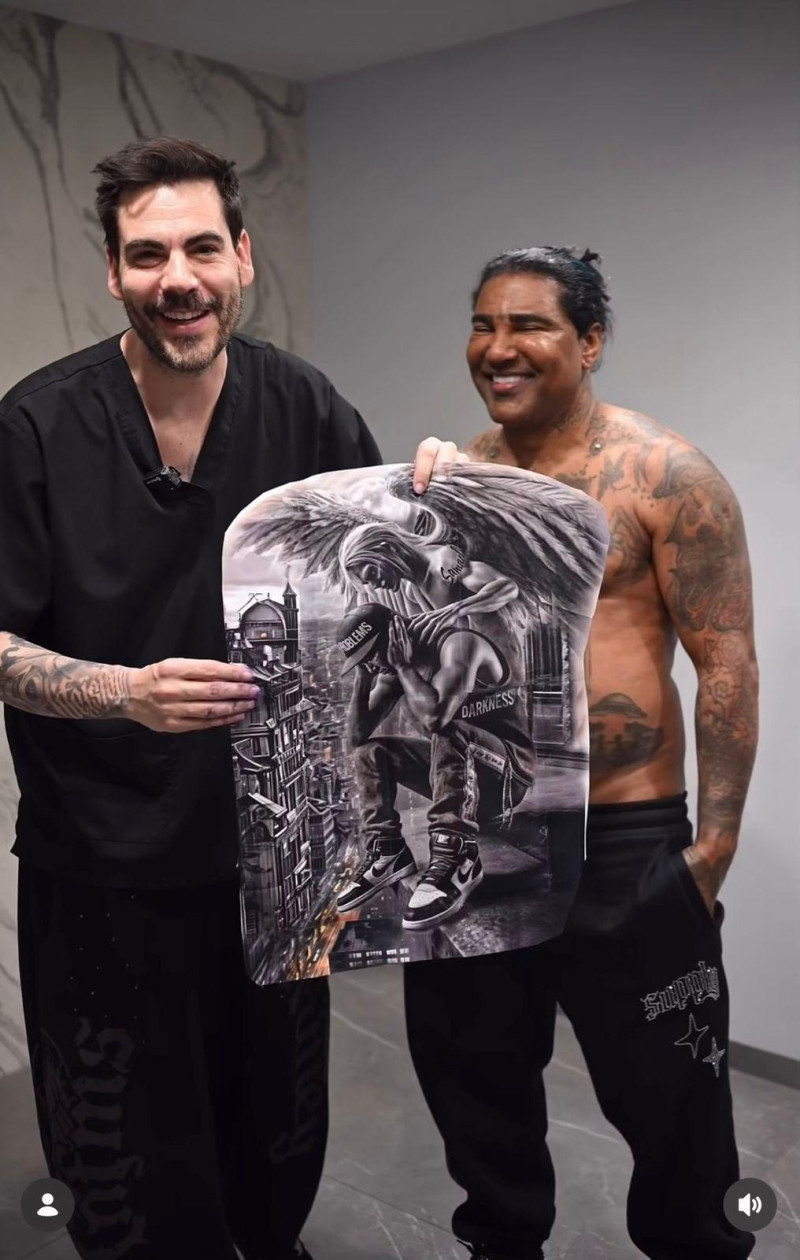 **Omega El Fuerte se tatúa la espalda completa durante procedimiento con sedación en España** El merenguero urbano Omega El Fuerte viajó a España para realizarse un tatuaje de un arcángel en toda la espalda, en un procedimiento que llamó la atención por llevarse a cabo bajo sedación intravenosa. El trabajo fue realizado por el tatuador Miguel Bohigues, quien mostró parte del proceso en sus redes sociales y explicó que, debido al tamaño y complejidad de la pieza, fue necesario utilizar anestesia para completar el diseño. Bohigues destacó que el artista permaneció tranquilo y relajado durante toda la sesión, acompañado por un equipo médico especializado. Además, agradeció públicamente la confianza de Omega y aseguró que disfrutó cada etapa del proceso, resaltando que cada tatuaje cuenta una historia especial. La técnica de sedación intravenosa suele emplearse en tatuajes extensos o de larga duración para facilitar la experiencia del paciente y permitir un trabajo más detallado. Más información en alodigitalrd.com. #OmegaElFuerte #Omega #Tatuajes #España #EntretenimientoRD #Farándula #AloRD #AloDigitalRD #NoticiasRD